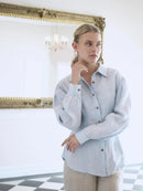 Woman wearing a light blue shirt in a room with decorative elements