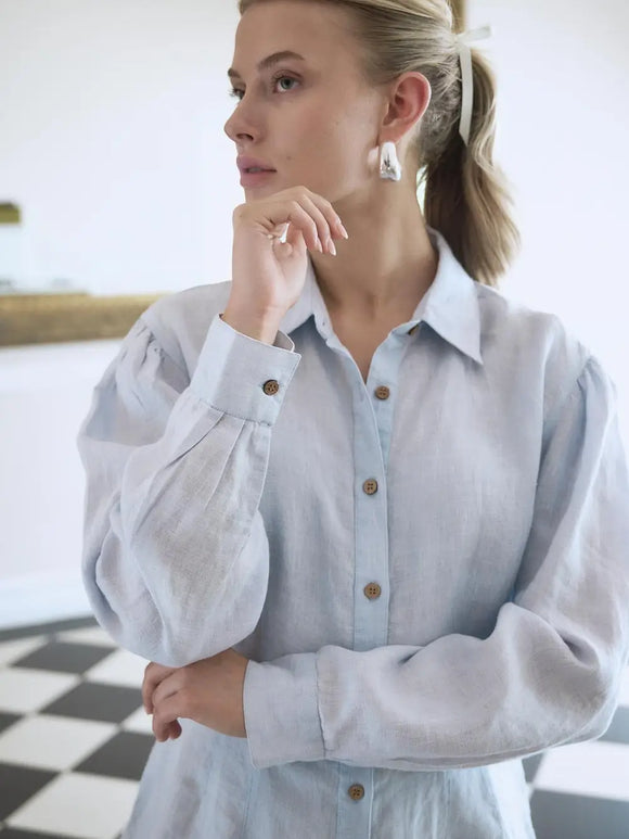 Woman wearing a light blue denim shirt with a blurred background
