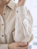 Close-up of a person wearing a beige button-up shirt with a blurred background. ethical women’s clothing.