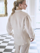 Woman wearing a beige outfit in a room with a checkered floor.